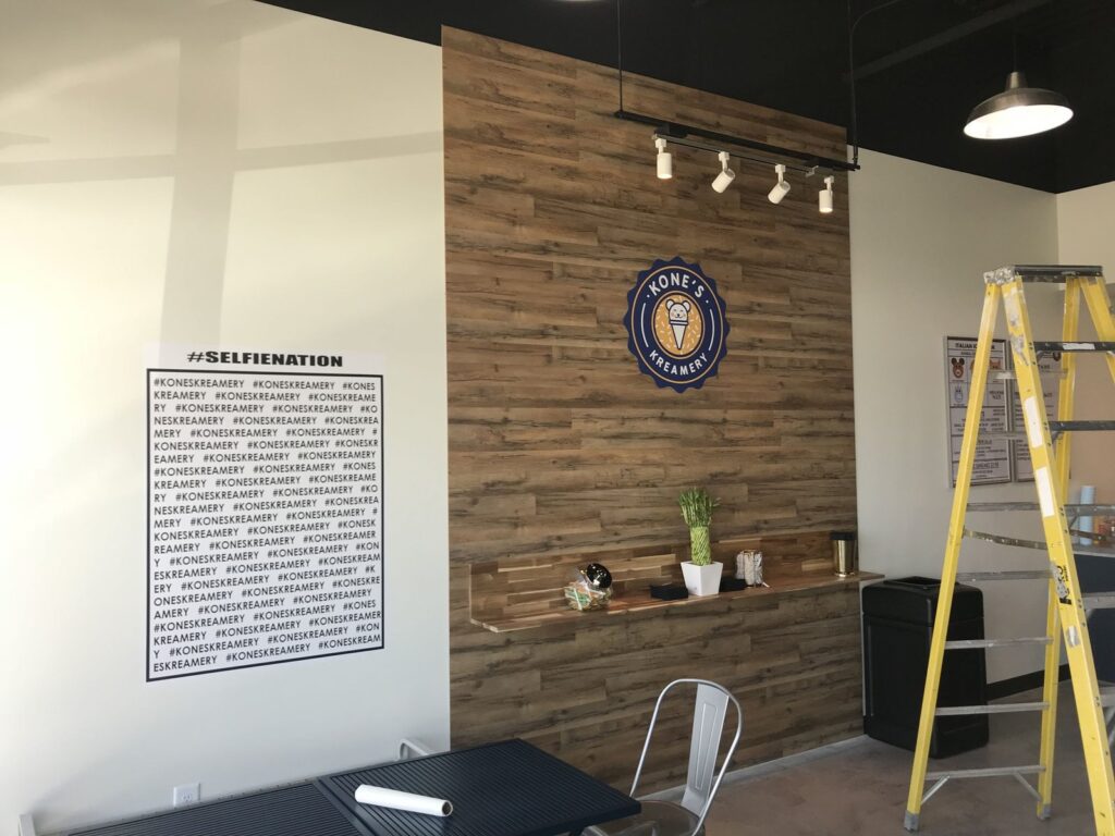 Kone’s Kreamery dining area with a wood accent wall, logo, and hashtag wall graphic in Fargo, North Dakota